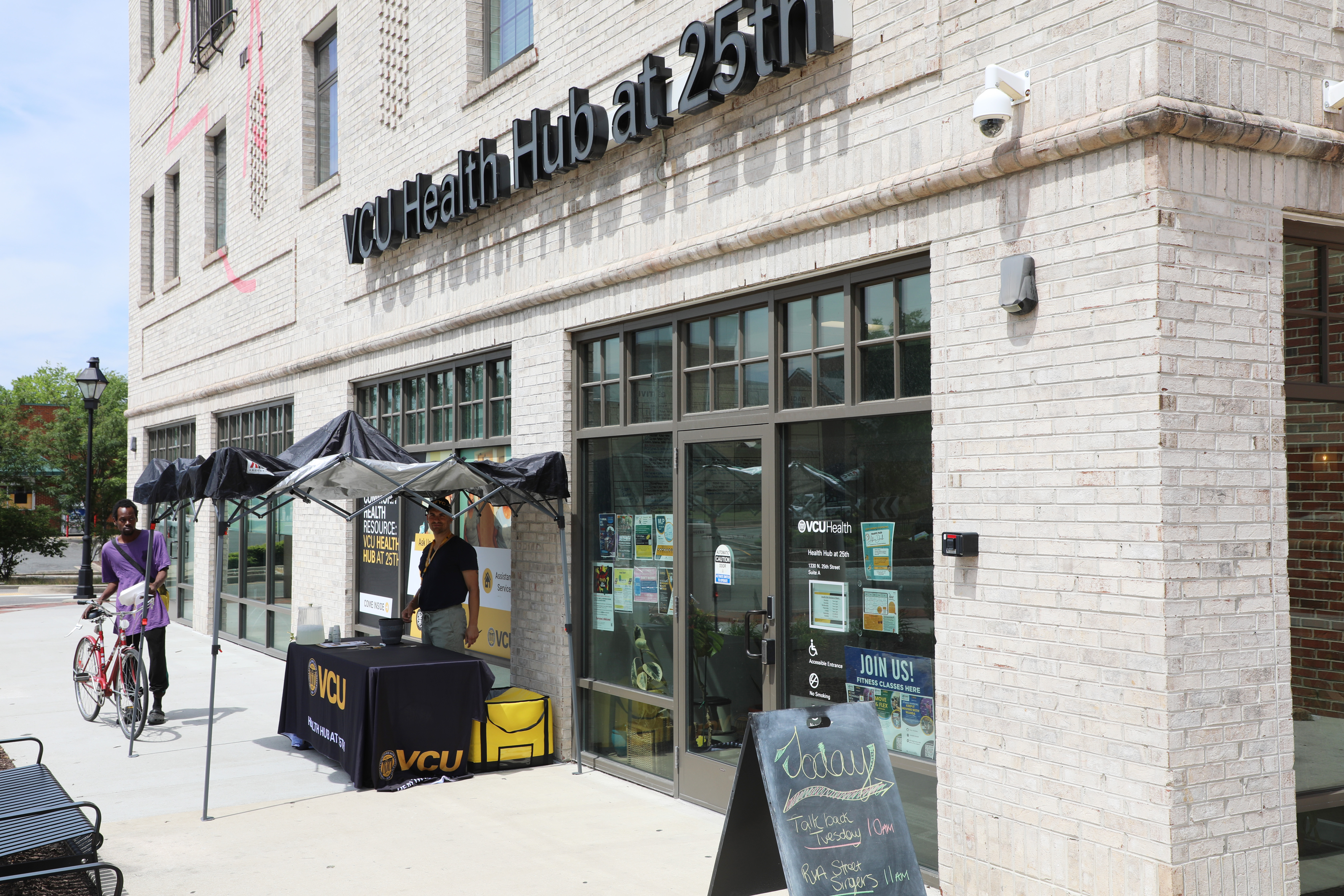 Exterior of the VCU Health Hub at 25th building with the main entrance and sidewalk activation table.